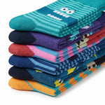 A stack of folded patterned socks on a white background, including teal with white cartoon eyes, purple, red, pink, navy, yellow, and orange designs.