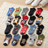 Assorted pairs of dog-themed socks on a textured surface with shoes in the background.