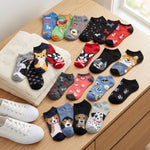 Assorted pairs of socks with dog designs on a wooden surface.