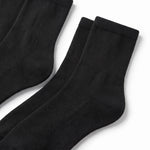 Three pairs of black ribbed crew socks arranged diagonally on a clean white background.