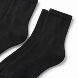 Three pairs of black ribbed crew socks arranged diagonally on a clean white background.