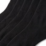 A close-up of black ribbed knit socks showing the texture and fold pattern against a white background.