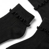 Black ribbed ankle socks with a ruffled trim at the top, arranged on a white background.