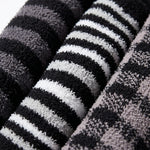 Close-up of folded plush towels with horizontal black, white, and gray stripes, showing the soft textured fabric.