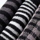 Close-up of folded plush towels with horizontal black, white, and gray stripes, showing the soft textured fabric.
