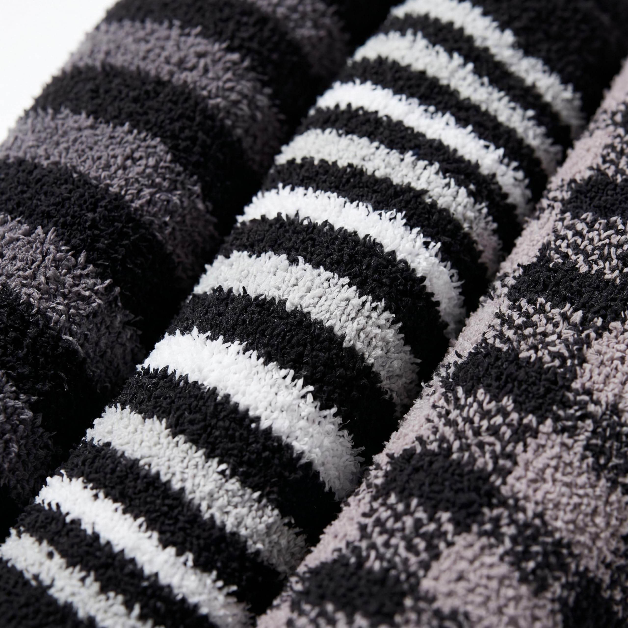 Close-up of folded plush towels with horizontal black, white, and gray stripes, showing the soft textured fabric.