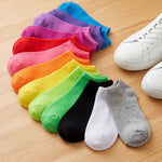 Colorful socks arranged in a semi-circle on a wooden surface with white sneakers.