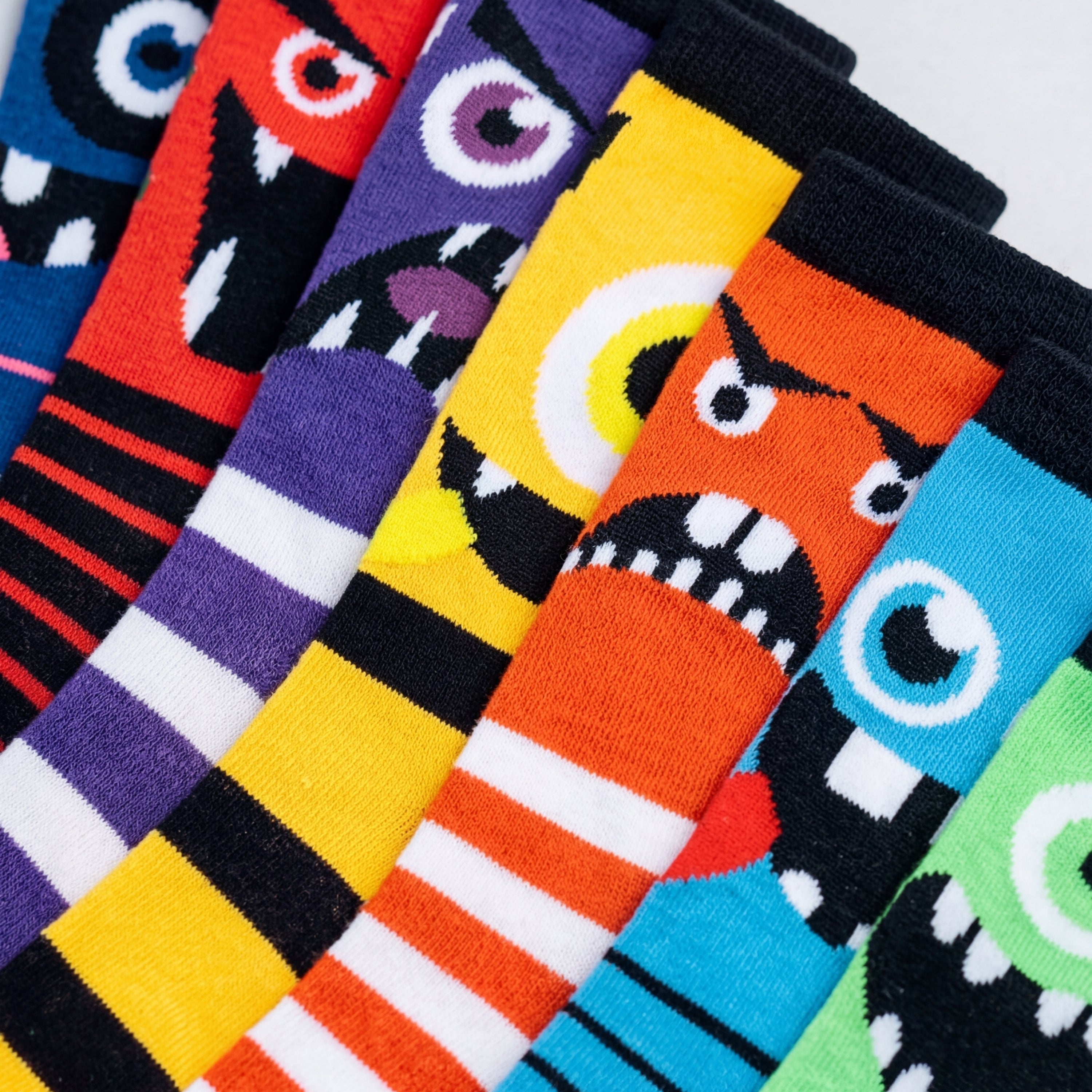 Colorful socks with cartoonish monster designs arranged in a row.