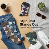 Patterned socks with jeans, sunglasses, and a cup on a wooden surface.