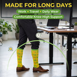 A person standing in an office wearing knee-high yellow patterned socks with green trim, black pants, and brown shoes. Large text at the top reads 'MADE FOR LONG DAYS' with 'Work • Travel • Daily Wear' and 'Comfortable Knee-High Support' in green banners.