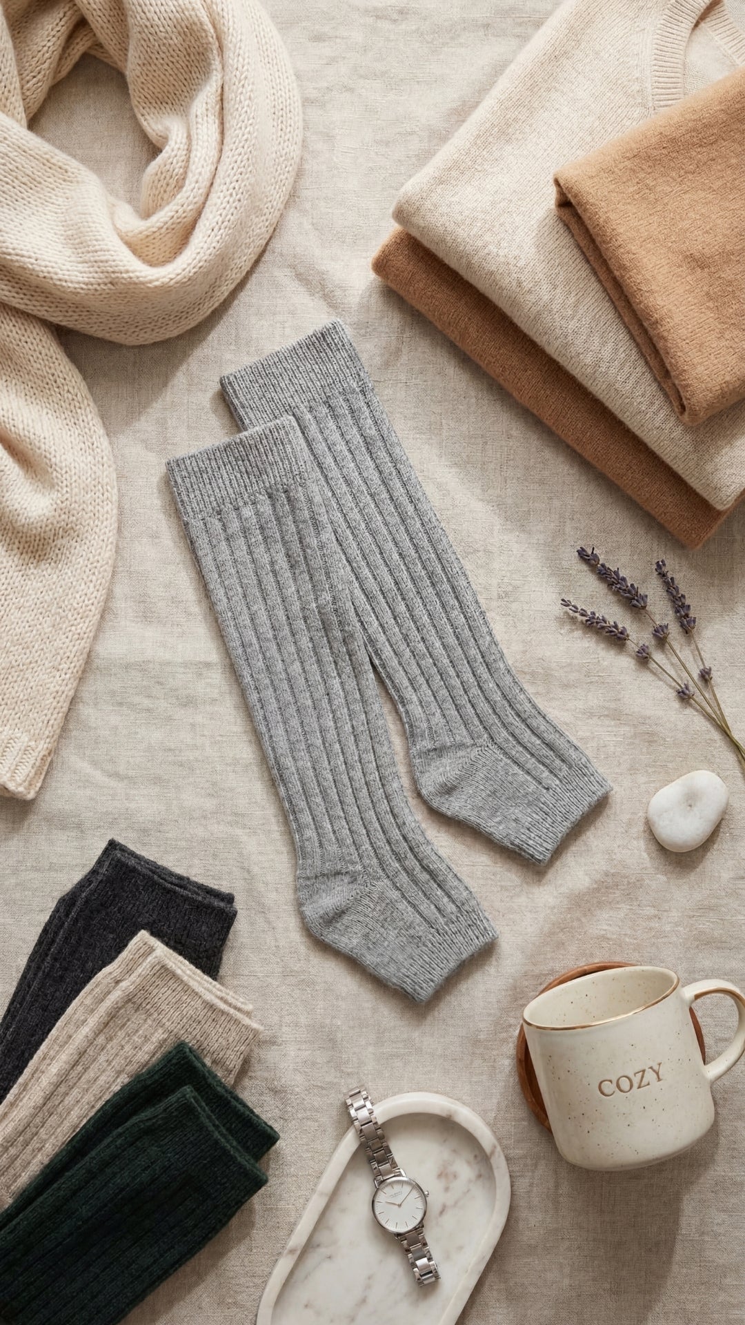 Gray knee-high socks on a textured surface with a mug labeled 'COZY' and lavender flowers.