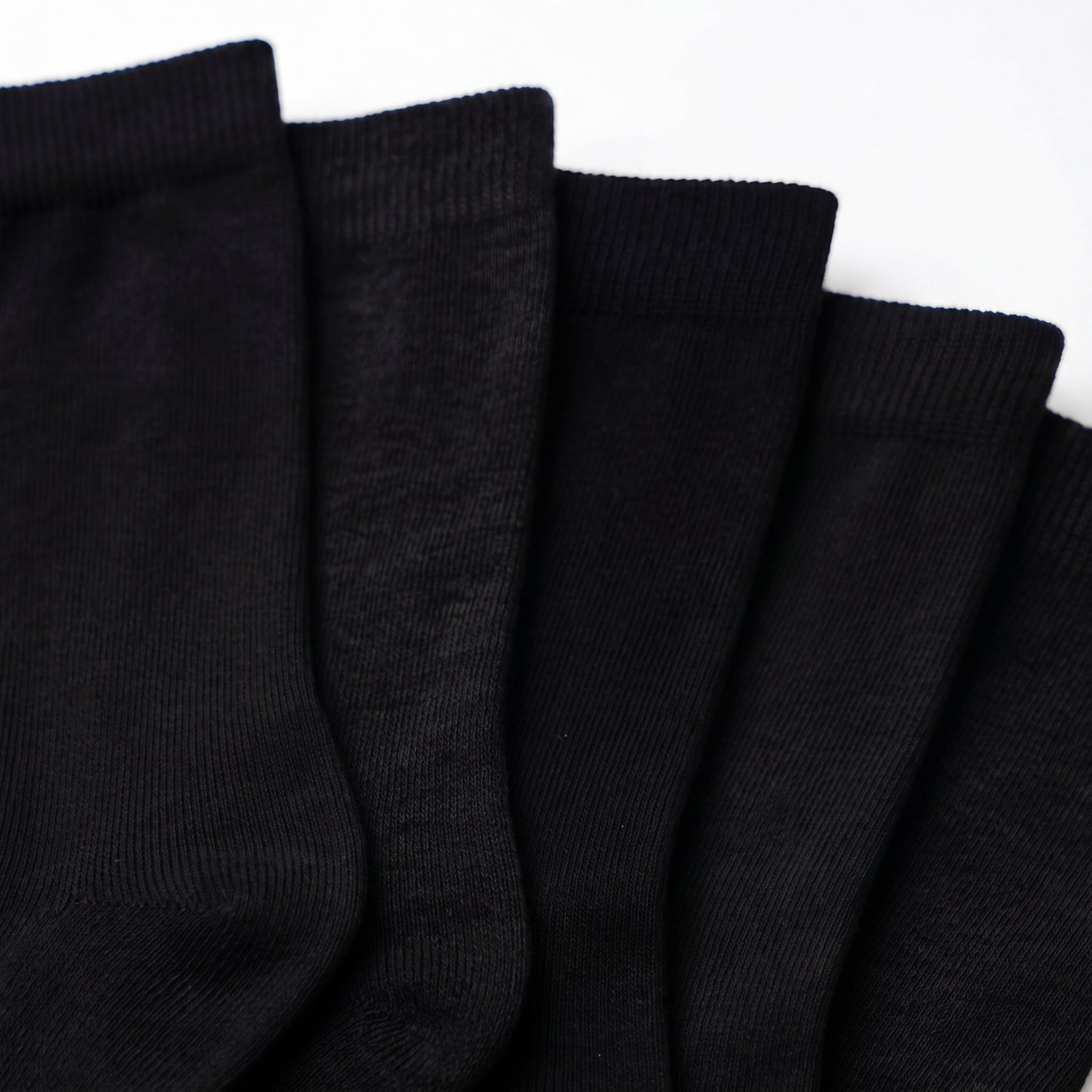 Five black ribbed knit socks fanned out against a plain white background.