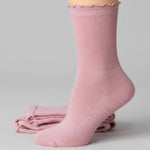 Pink sock with scalloped edge on a light gray background