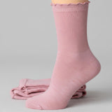Pink sock with scalloped edge on a light gray background