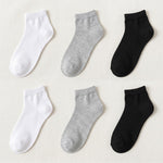 Six ankle socks arranged in a 2x3 grid on a light beige fabric background, showing white, light heather gray, and black options.