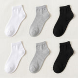 Six ankle socks arranged in a 2x3 grid on a light beige fabric background, showing white, light heather gray, and black options.