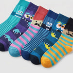 Six colorful children's socks arranged in a fan shape on a light gray background. Each sock features a different cartoon monster or character design with stripes and solid sections in teal, purple, pink, red, navy, blue, yellow, and orange.