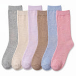 Six pairs of crew socks in different soft colors, arranged side by side on a white background. The colors are heather gray, cream, light lavender, tan, light blue, and dusty pink.