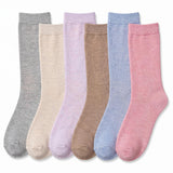 Six pairs of crew socks in different soft colors, arranged side by side on a white background. The colors are heather gray, cream, light lavender, tan, light blue, and dusty pink.