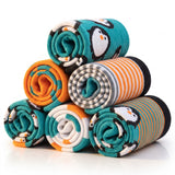 Six rolled pairs of socks stacked in a pyramid on a white background. The socks feature penguin and striped patterns in teal, orange, black, white, and gray.
