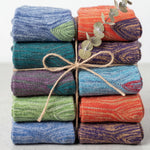 Stack of colorful folded fabrics tied with twine on a light background