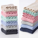 Stacks of folded ruffled fabric in various colors on a white background