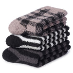 Three folded plush socks stacked on a white background, featuring different patterns: a taupe and black checkered top sock, a black and white striped middle sock, and a dark gray and black striped bottom sock.
