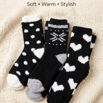 Three pairs of black socks with white and gray patterns on a beige fabric background.