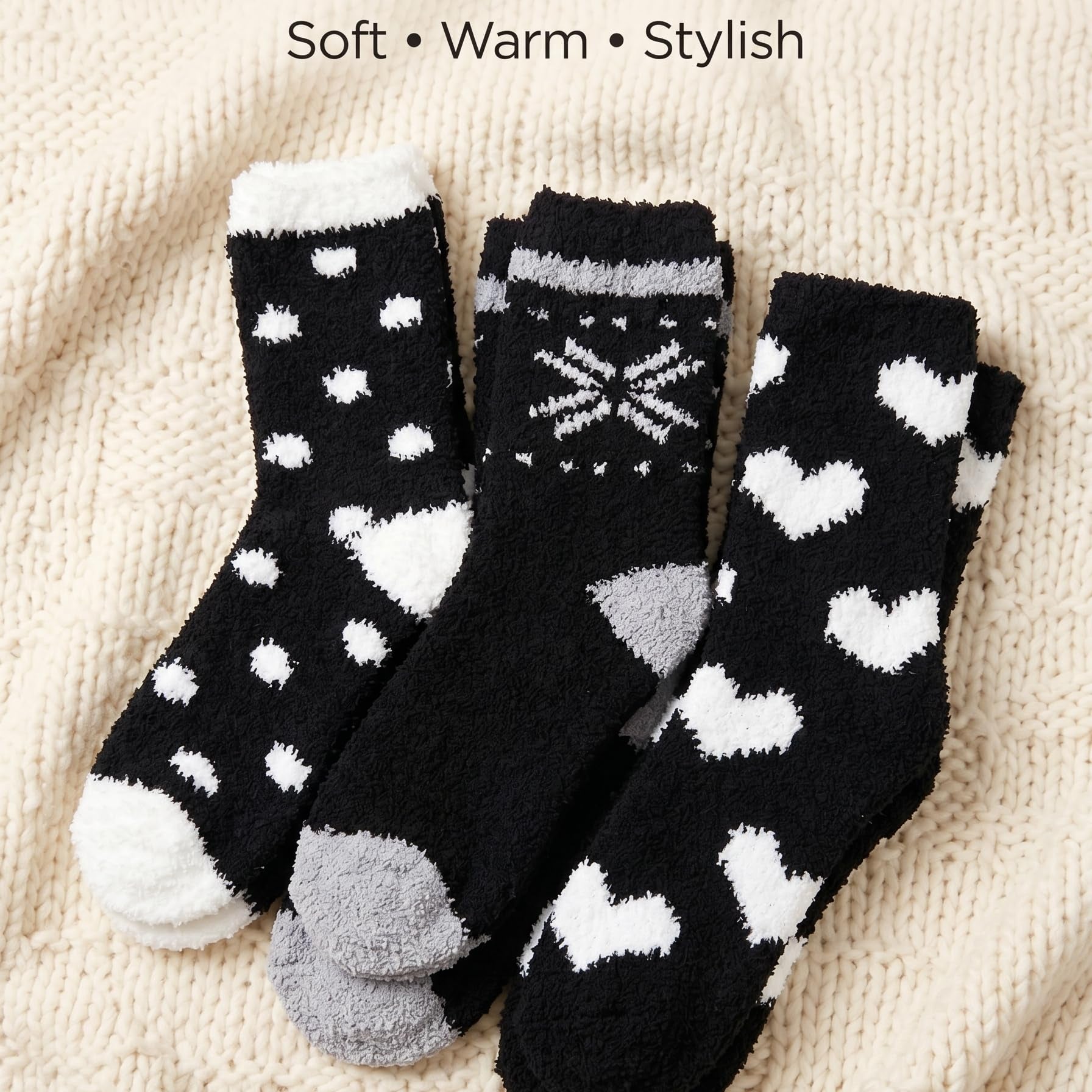 Three pairs of black socks with white and gray patterns on a beige fabric background.