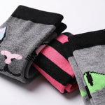 Three pairs of folded crew socks displayed on a white background. The left pair is gray with a black cuff and a pink and black abstract graphic.