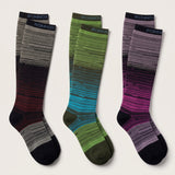 Three pairs of knee-high socks by Ronnox with horizontal striped gradient patterns, displayed on a light beige background. The left pair transitions from gray and black to dark red and black.