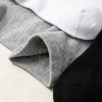 Three pairs of ribbed knit socks stacked diagonally, showing gray, white, and black colors with a close-up of the gray cuff texture.