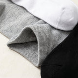 Three pairs of ribbed knit socks stacked diagonally, showing gray, white, and black colors with a close-up of the gray cuff texture.