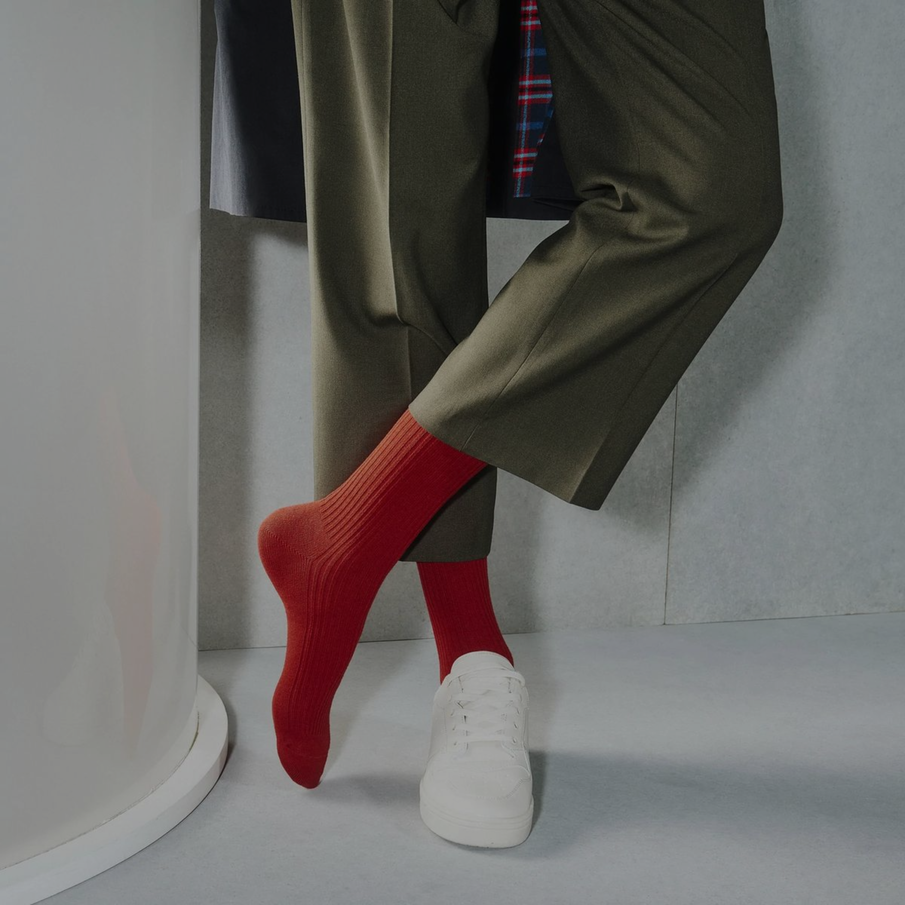 Person wearing red socks, white sneakers, and a green coat with a plaid tie.