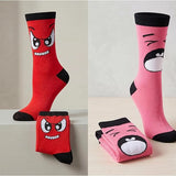 Two pairs of socks with cartoon face designs on a neutral background