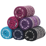 Six rolled knit blankets in assorted colors, including purple, pink, blue, navy, and black, each featuring a white Fair Isle pattern, arranged in a pyramid on a white background.
