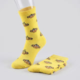 Yellow crew socks with a repeating cartoon monkey face pattern, shown on a mannequin foot with one folded pair on a light gray background.