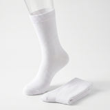 A pair of plain white crew socks, with one sock displayed on a clear mannequin foot and the other folded neatly beside it, set against a seamless white studio background.