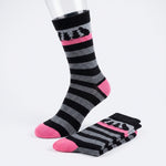 A pair of crew socks with black and gray horizontal stripes, featuring a pink band near the cuff with black cat silhouettes and bright pink toes and heels. One sock is displayed on a clear mannequin leg, while the other is folded on a white studio background.