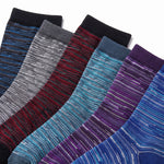 Six pairs of crew socks fanned out diagonally, showcasing different colorways with a marled stripe pattern. The colors include navy, gray, red, black, teal, and purple, set against a clean white background.